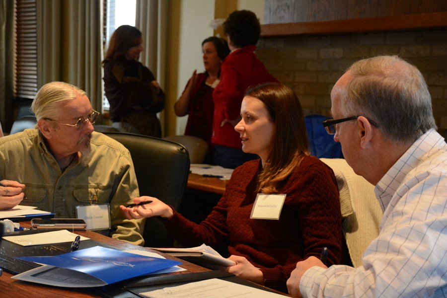 three people sitting at a table talking in a meeting setting