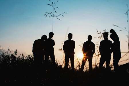 Silhouettes of young people standing in a field.
