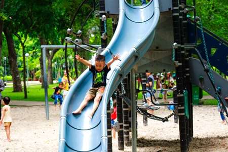 A child slides down a slide on a busy playground.